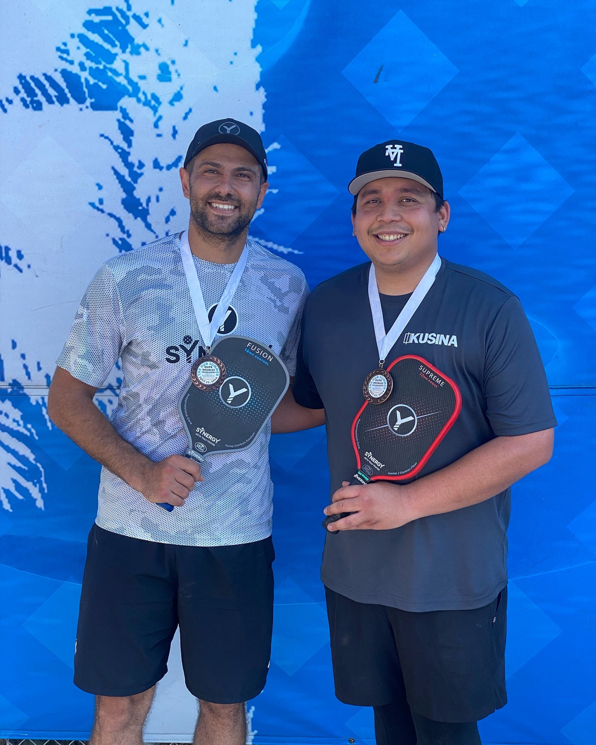 Real pickleball players holding Synergy paddles and medals