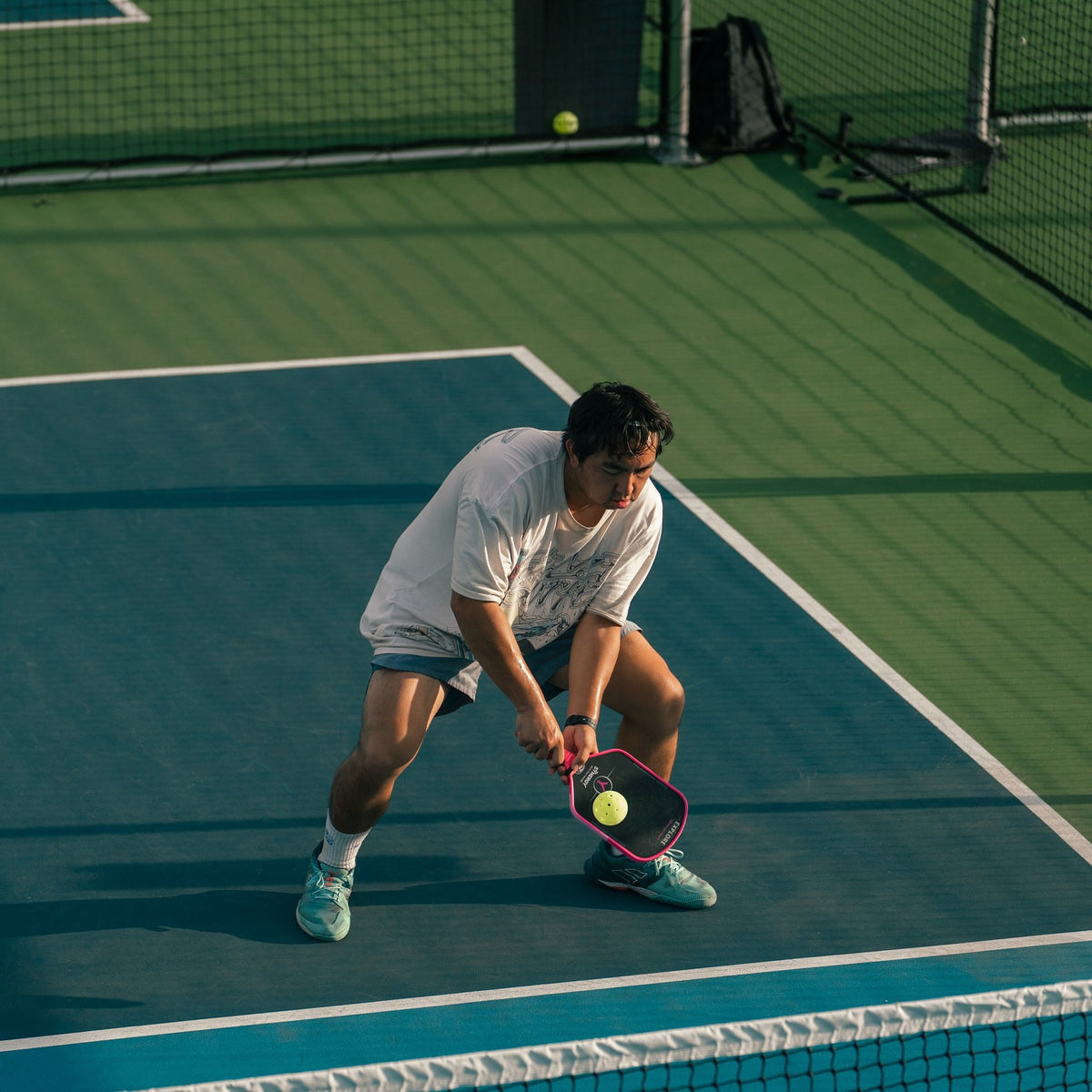 Real player returning a pickleball with a pink Synergy paddle