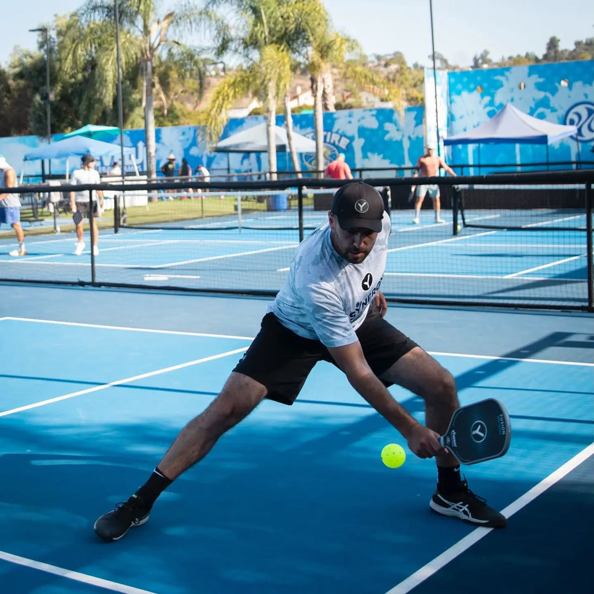 Real Synergy player reaching for a pickleball outdoors